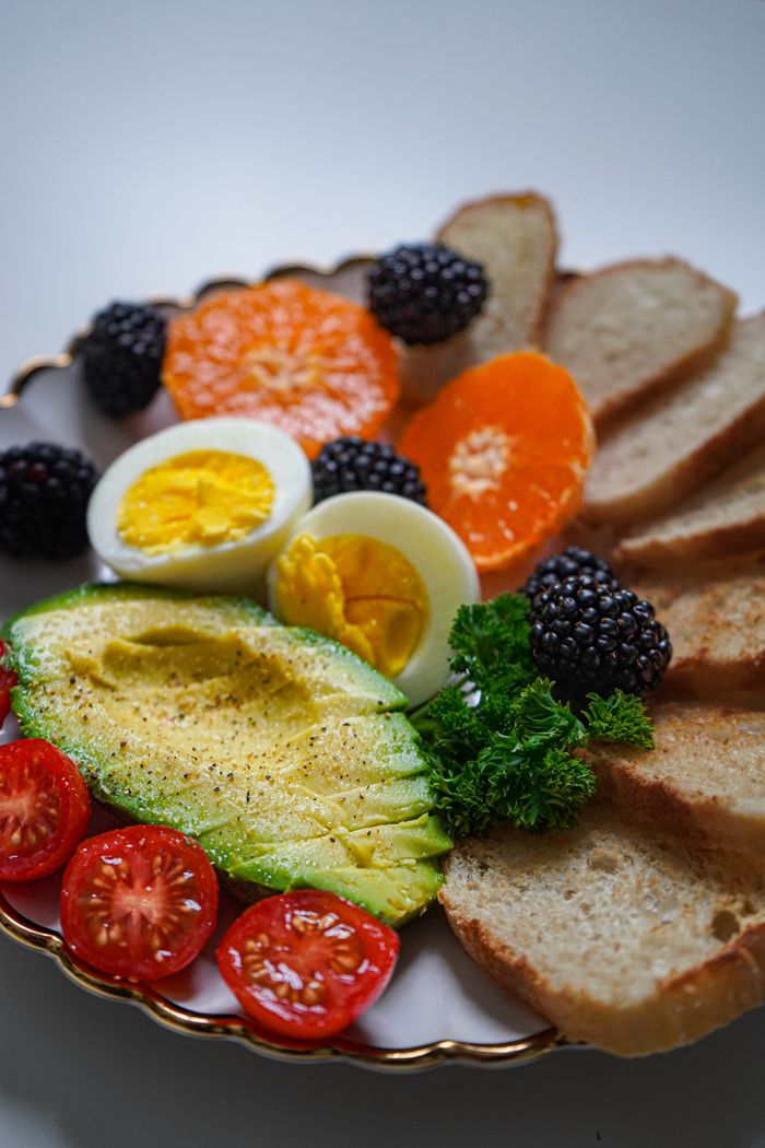 services-01 Vibrant breakfast plate with fresh avocado, eggs, and assorted fruits.