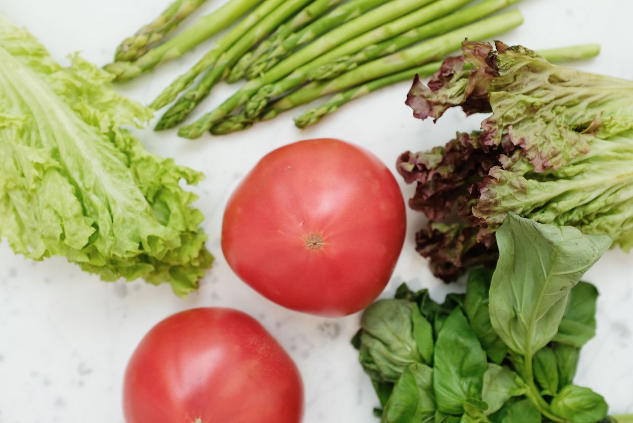 hero-img-02 Top view of fresh asparagus, lettuce, basil, and tomatoes, highlighting healthy and nutritious ingredients.
