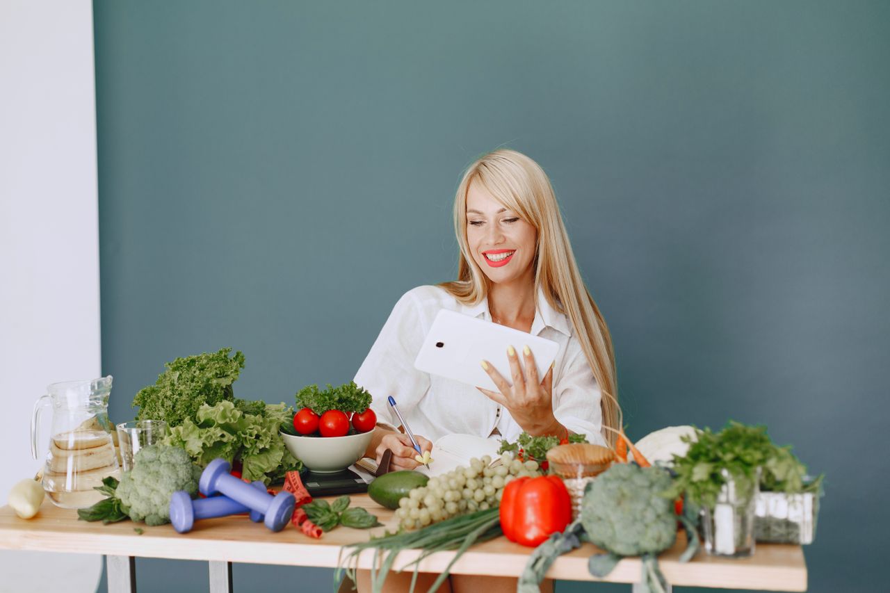 services-03 Woman using a tablet surrounded by fresh vegetables at a table, showcasing healthy lifestyle and technology.